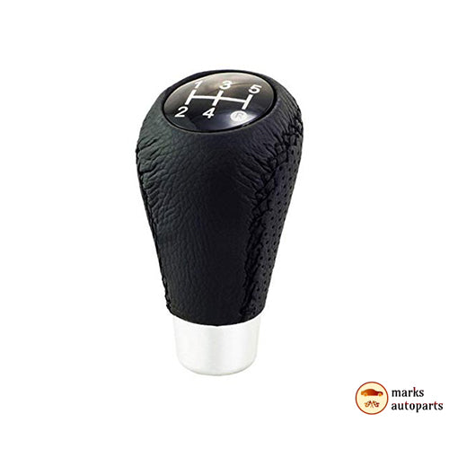 A circular shift knob with a white and black stem with gears written from 1 to 6 on a black inner circle slanted left towards the screen.